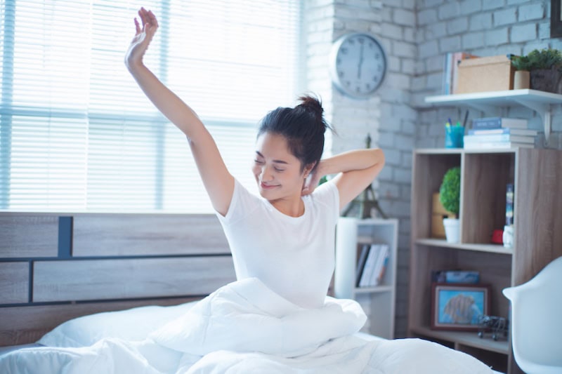 woman waking up in bed, feeling refreshed.